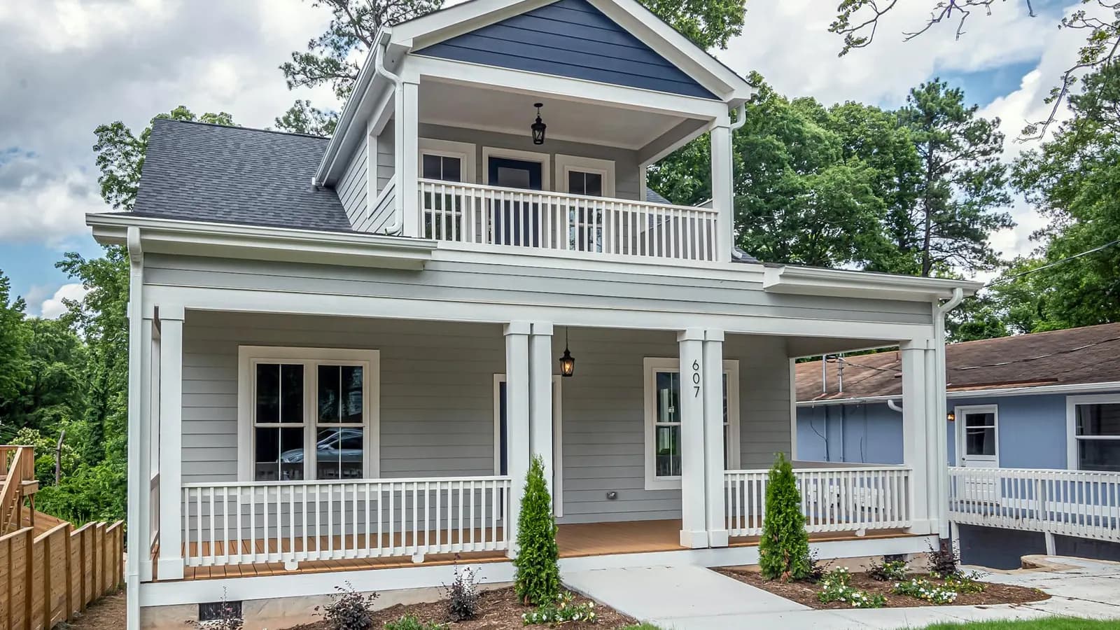 Light gray Craftsman-style home with a full front porch, tapered columns, and a second-story balcony