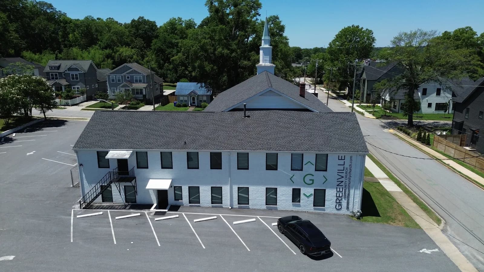 Aerial view of Greenville Community Church — a renovated white-brick two-story building with a white steeple, completed by BHR Construction