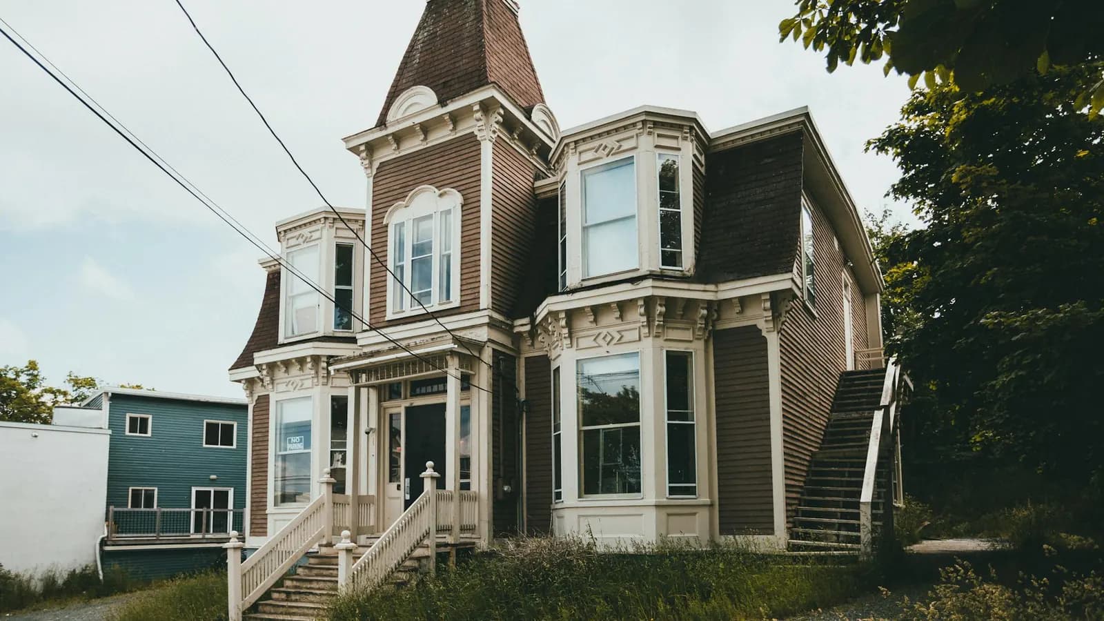 Ornate Victorian-style house with a corner tower, bay windows, a steep roof, and painted trim